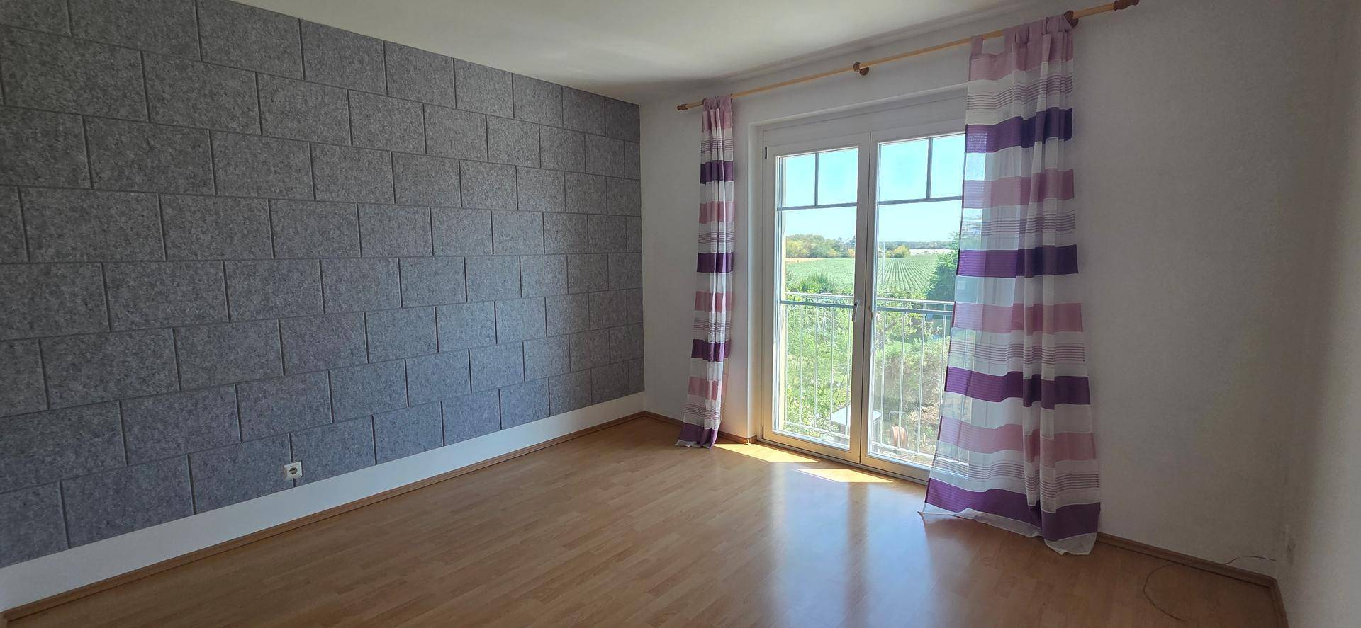 Schlafzimmer mit Laminatboden, Akzentwand und französischem Balkon mit Weitblick.