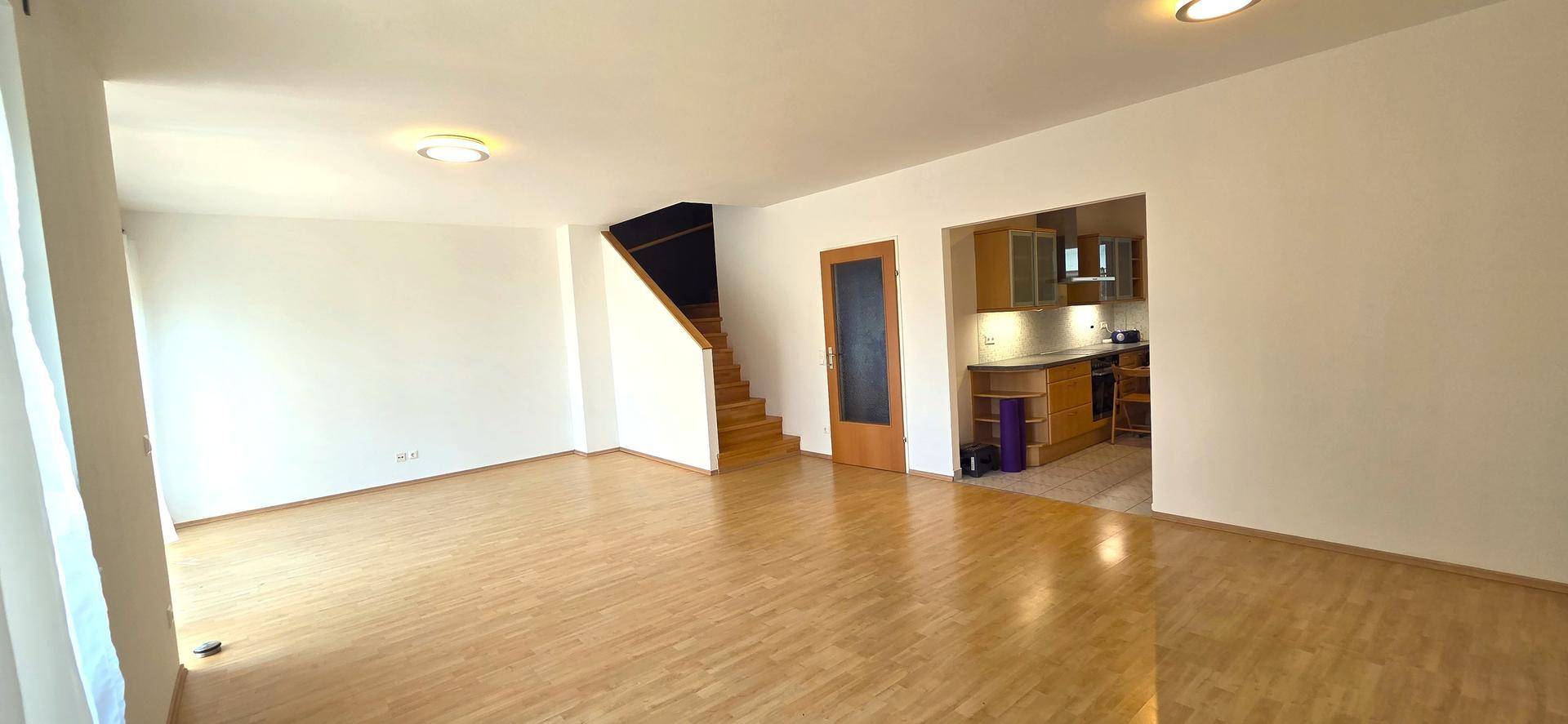 Offener Wohnbereich mit Laminatboden und Blick auf die angrenzende Küche und Treppe.