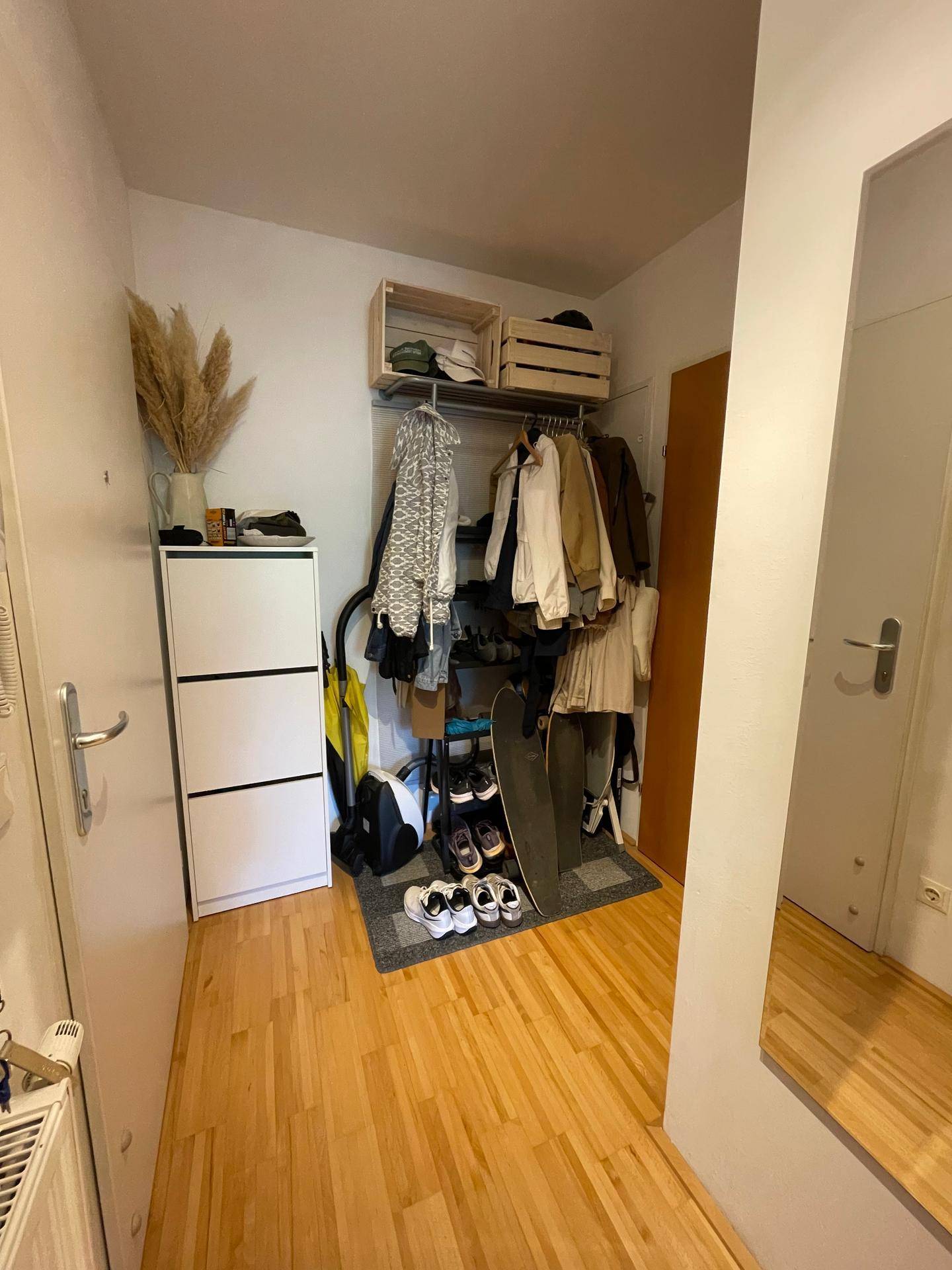Flur mit Schuhschrank, offener Garderobe und großem Spiegel, bietet praktischen Stauraum für Kleidung.