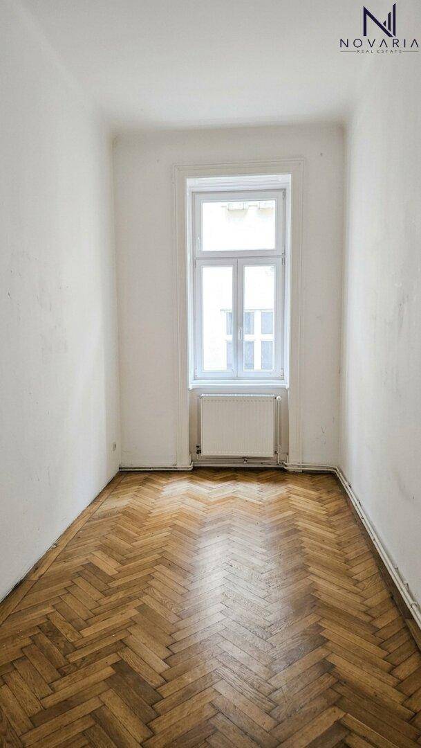 Gemütliches Zimmer mit Fischgrätparkett und einem Fenster, das den Raum mit Licht erfüllt.
