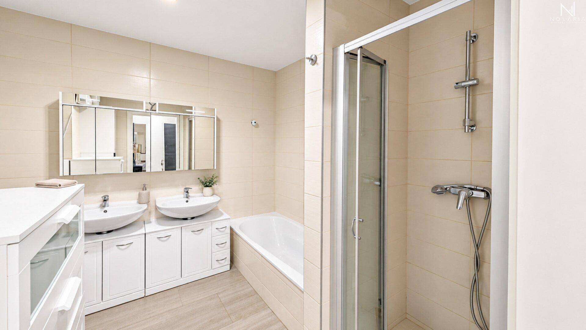 Helles Badezimmer mit Doppelwaschbecken, Badewanne und separater Duschkabine.