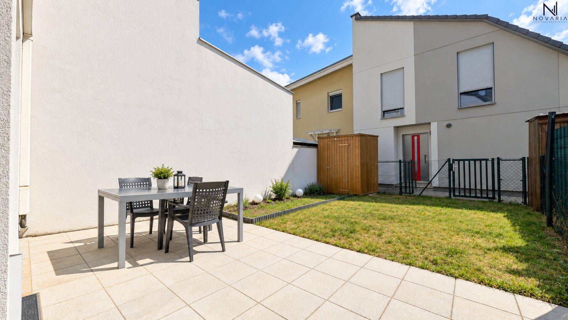 Sonnenverwöhnter Gartenbereich mit großer Terrasse, Rasenfläche und Sitzgelegenheiten im Freien.