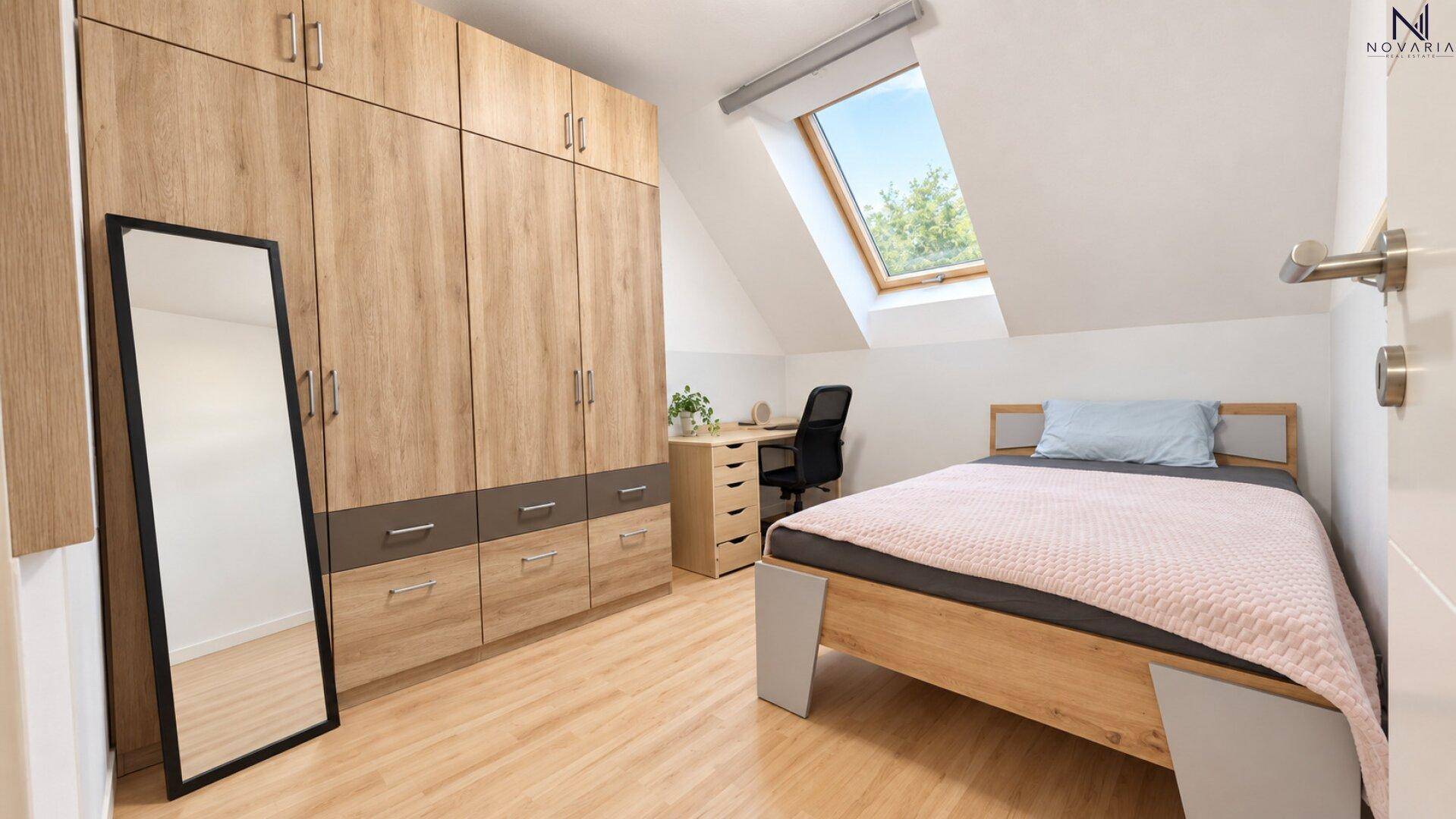 Helles Schlafzimmer im Dachgeschoss mit großem Kleiderschrank, Schreibtisch und Dachfenster.