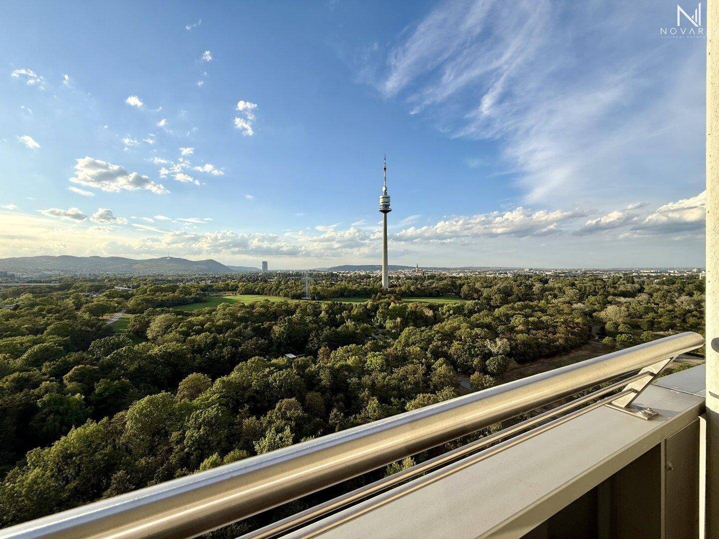 Weitläufiger Ausblick vom Balkon auf die Stadtlandschaft, den Donauturm und grüne Flächen.