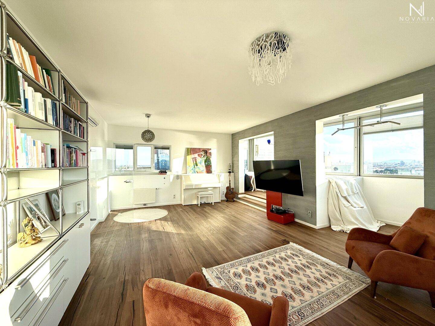 Geräumiges Wohnzimmer mit Holzboden, Klavier und großen Fenstern, die viel Tageslicht hereinlassen.