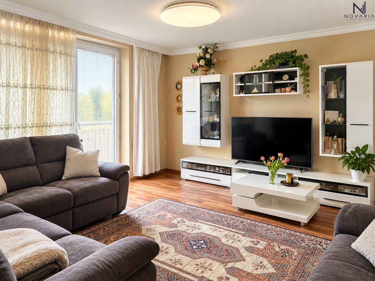 Gemütliches Wohnzimmer mit Sofa, Teppich und Zugang zum Balkon.