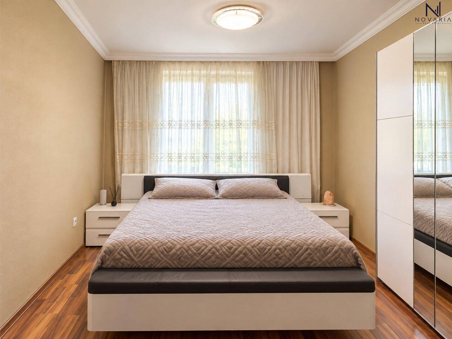 Schlafzimmer mit Doppelbett, Nachttischen und Spiegelschrank.