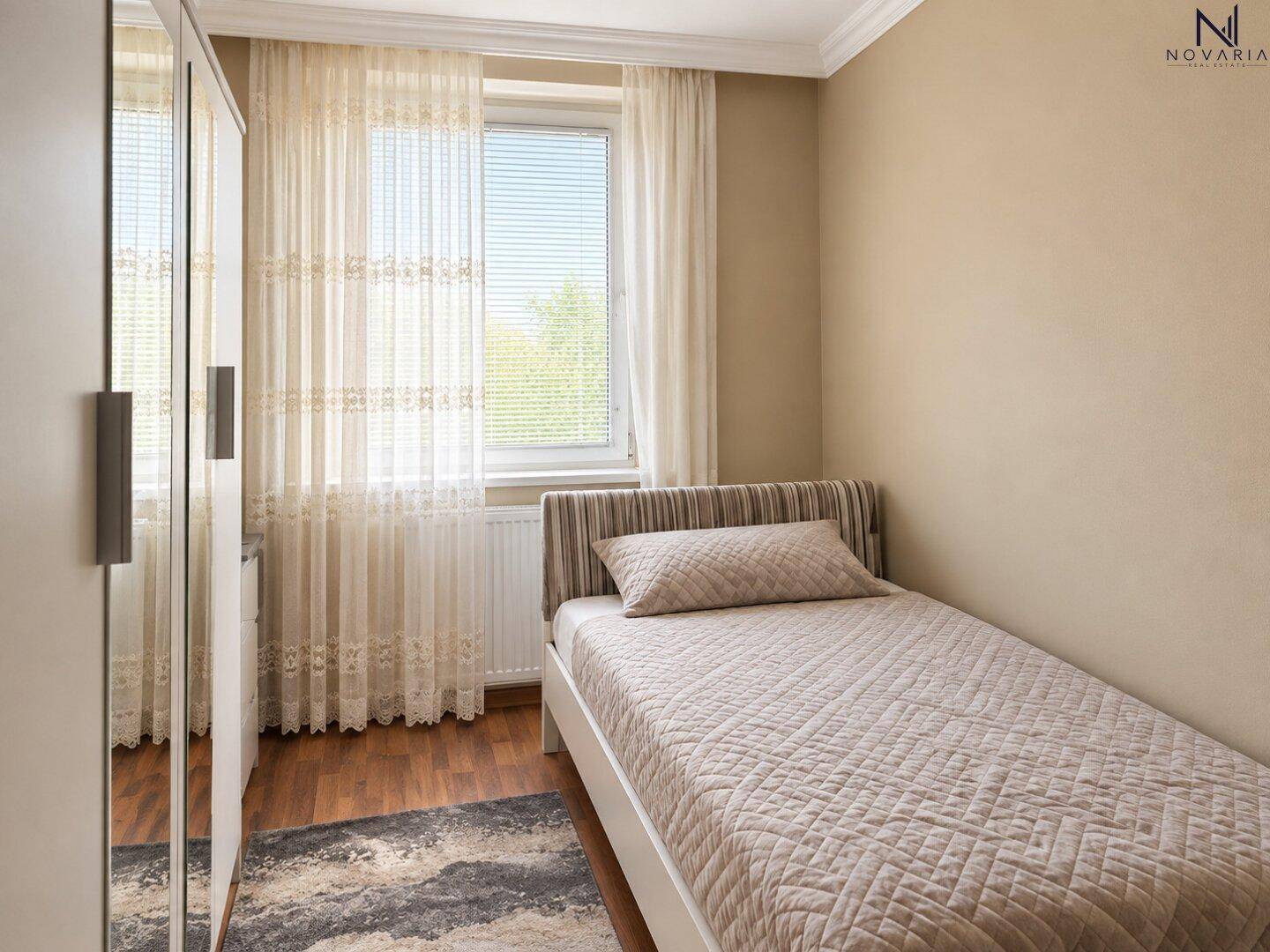 Kleines Schlafzimmer mit Einzelbett, Teppich und Fenster.