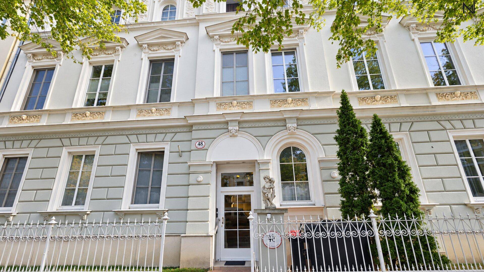 Elegante Fassade eines Altbaus mit reich verzierten Fenstern und klassischer Architektur.