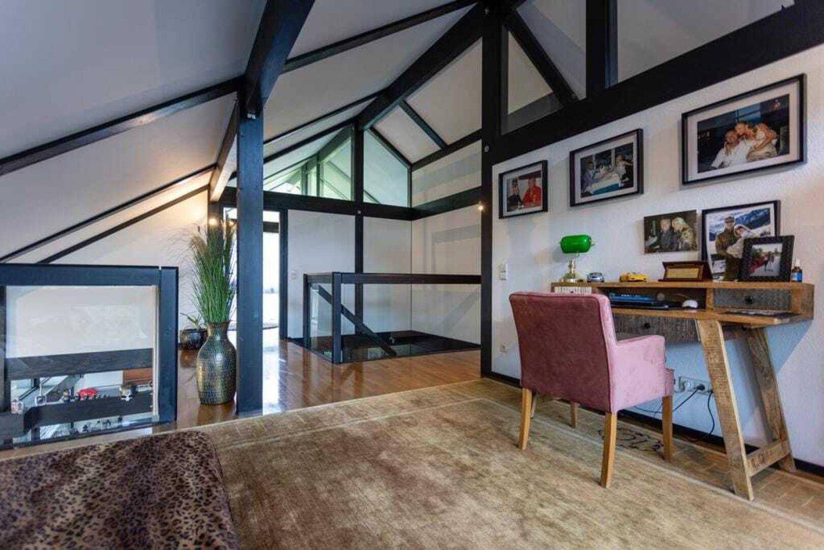 Helles Arbeitszimmer im Obergeschoss mit Holzboden, Blick auf den unteren Bereich und schrägen Decken.