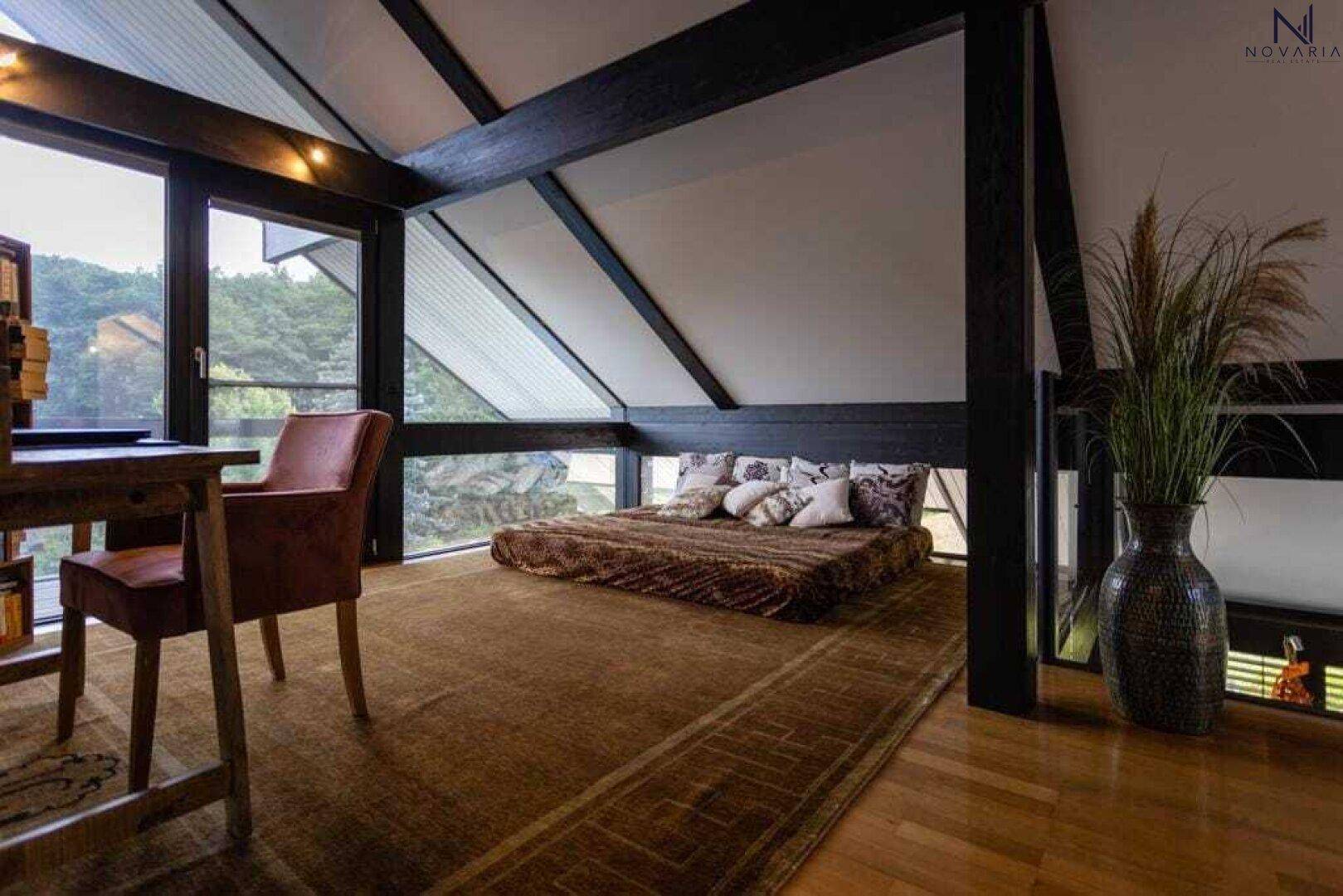Gemütliches Schlafzimmer im Dachgeschoss mit Holzboden, großen Fenstern und schrägen Decken.
