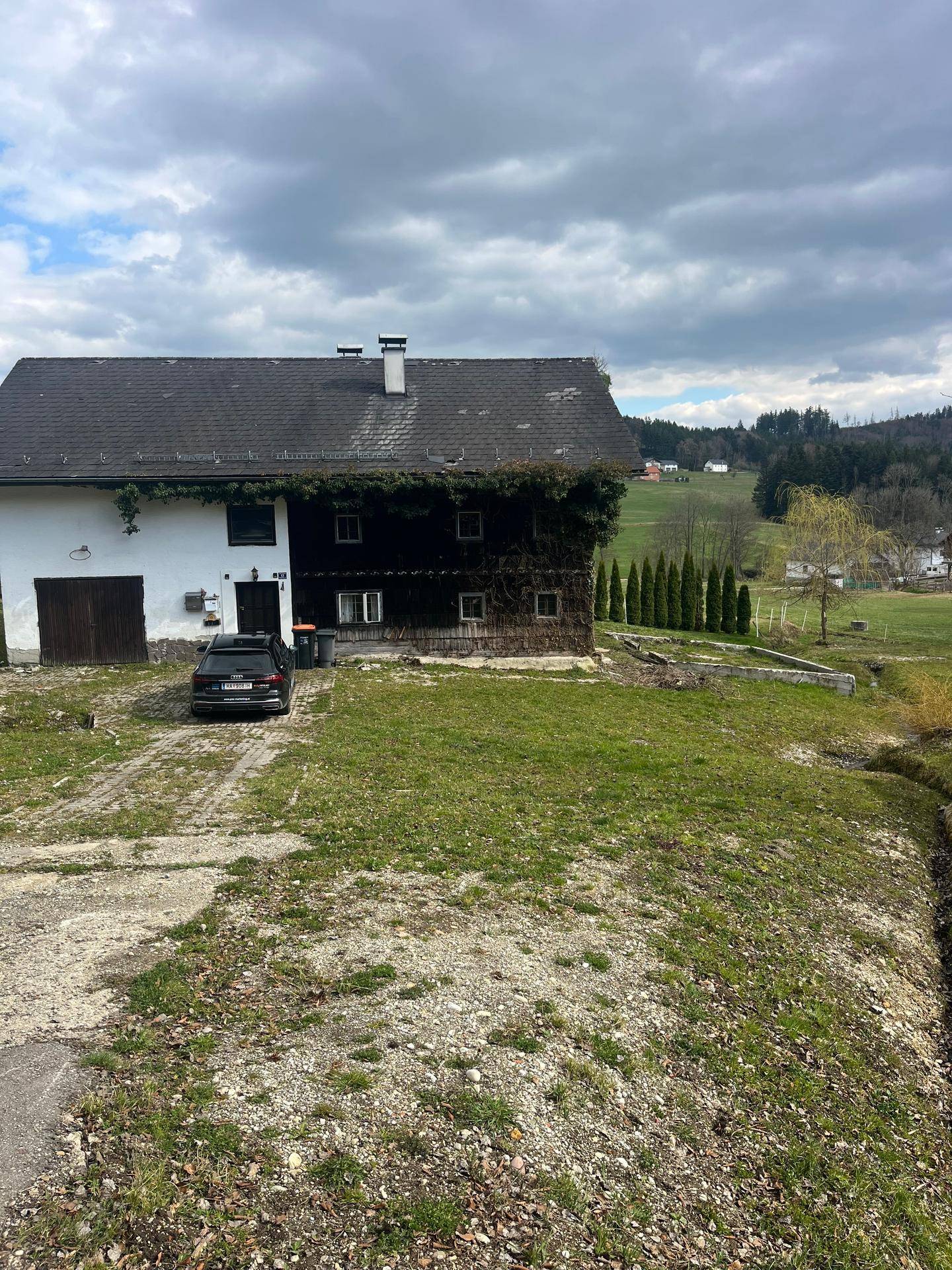 Gesamtansicht des Anwesens mit dem weißen und dem Holzhaus, umgeben von Natur.