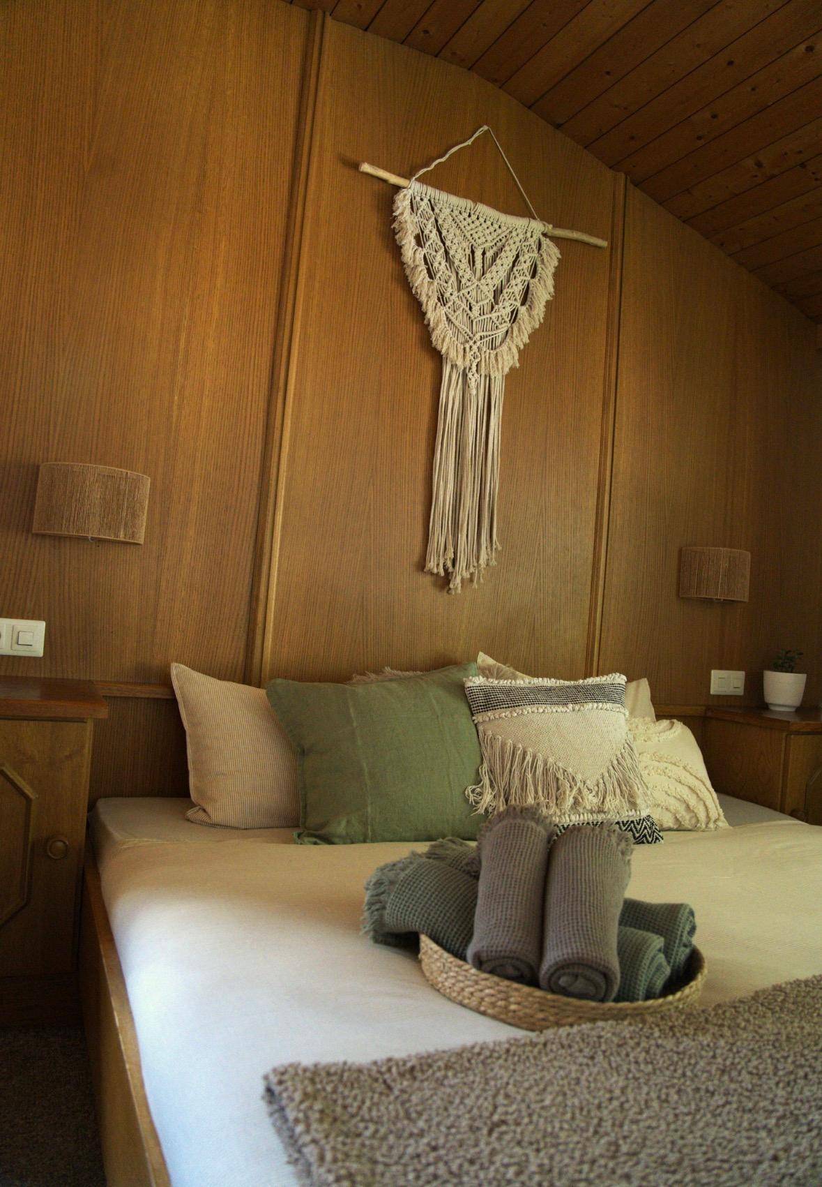 Gemütliches Schlafzimmer mit Holzwänden, bequemen Kissen und rustikaler Dekoration.
