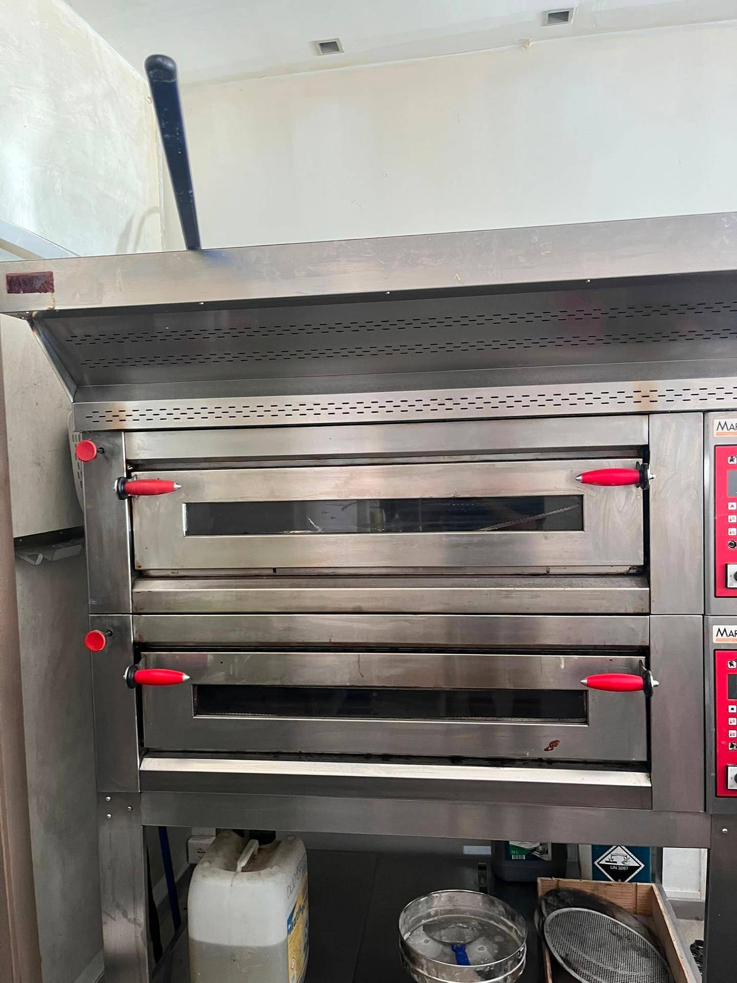 Großer doppelstöckiger Industrieofen aus Edelstahl mit roten Griffen für professionelles Backen.