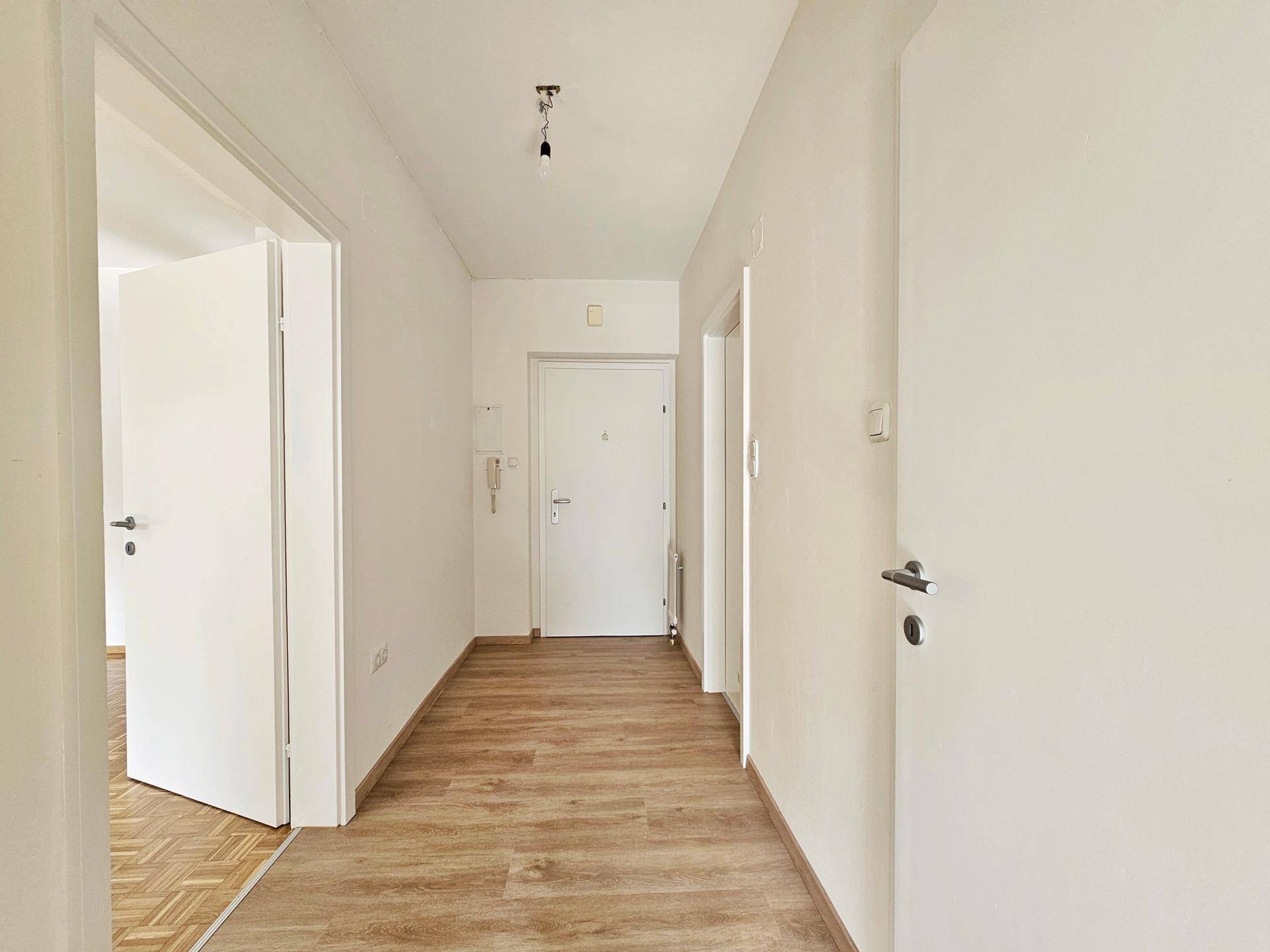 Heller Flur mit Holzoptikboden und mehreren weißen Türen, die zu verschiedenen Räumen führen.