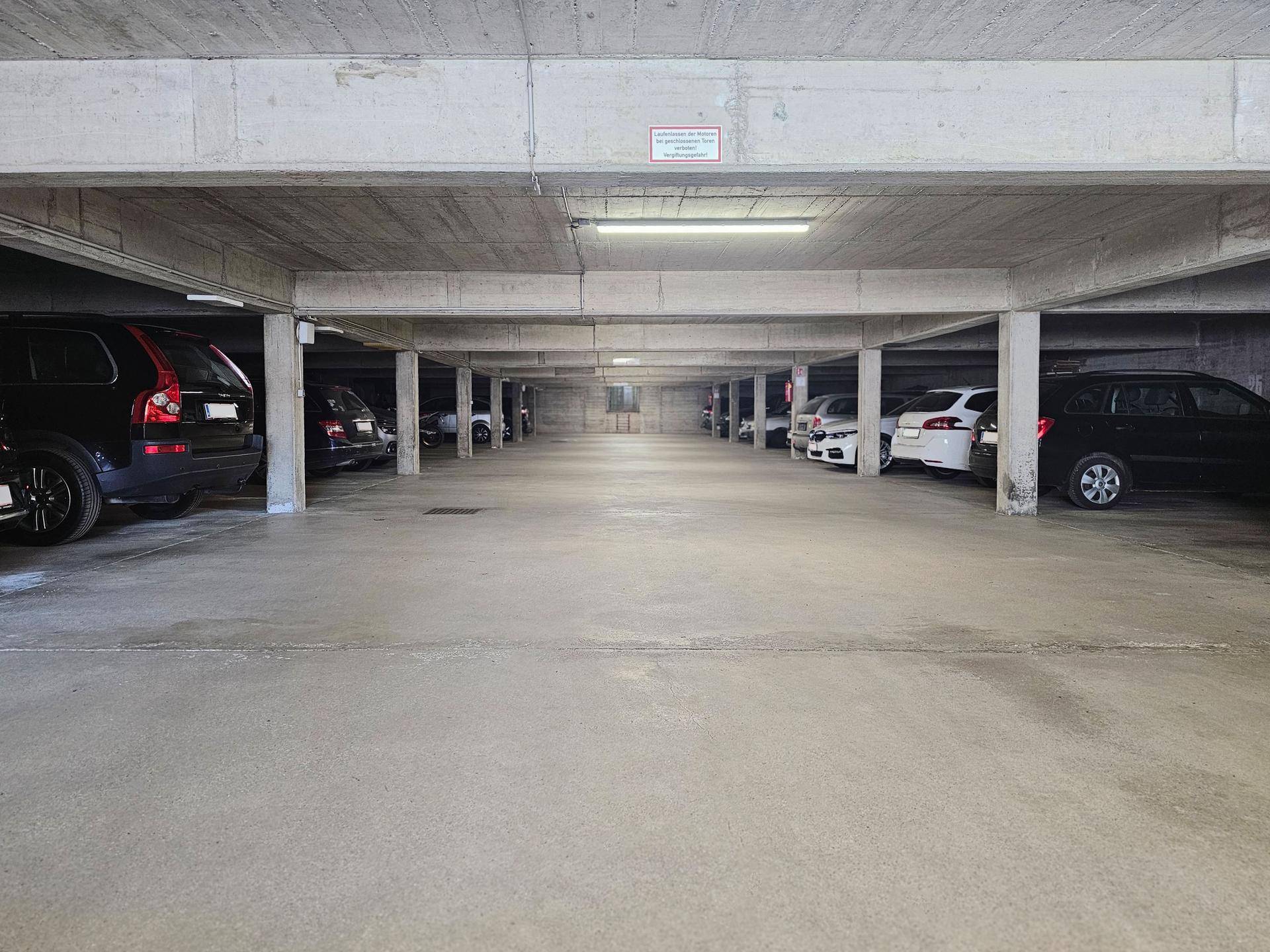 Geräumige Tiefgarage mit vielen Parkplätzen und Betonkonstruktion unter einem Gebäude.