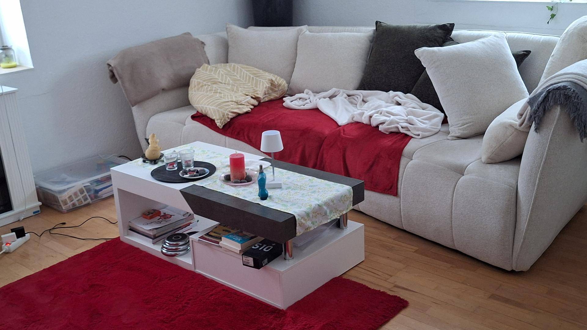 Gemütliches Wohnzimmer mit beigem Sofa, Couchtisch und Holzboden.