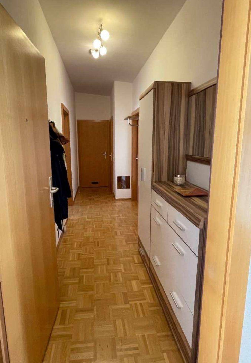 Heller Flur mit Parkettboden, Schuhschrank und Garderobe, einladend gestaltet.