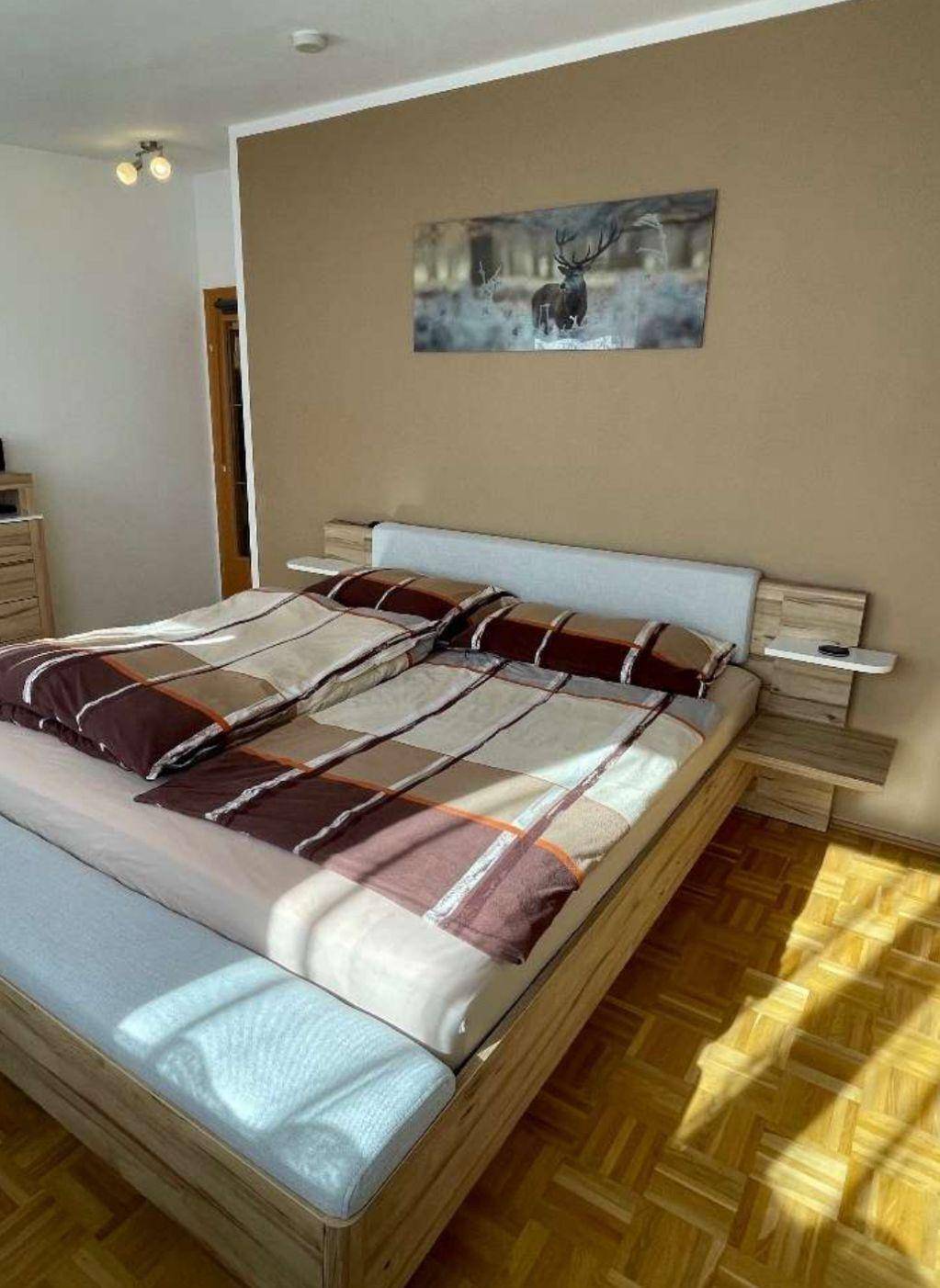 Schlafzimmer mit Holzbett, Nachttischen und Parkettboden, hell und einladend gestaltet.