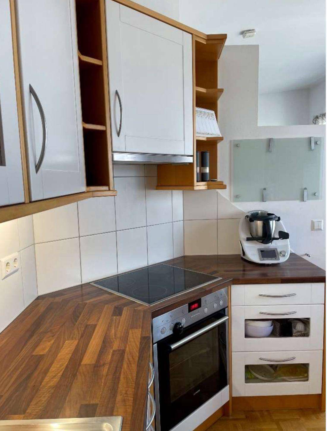 Moderne Küche mit Holzarbeitsplatten, Induktionskochfeld und Backofen, hell und funktional.