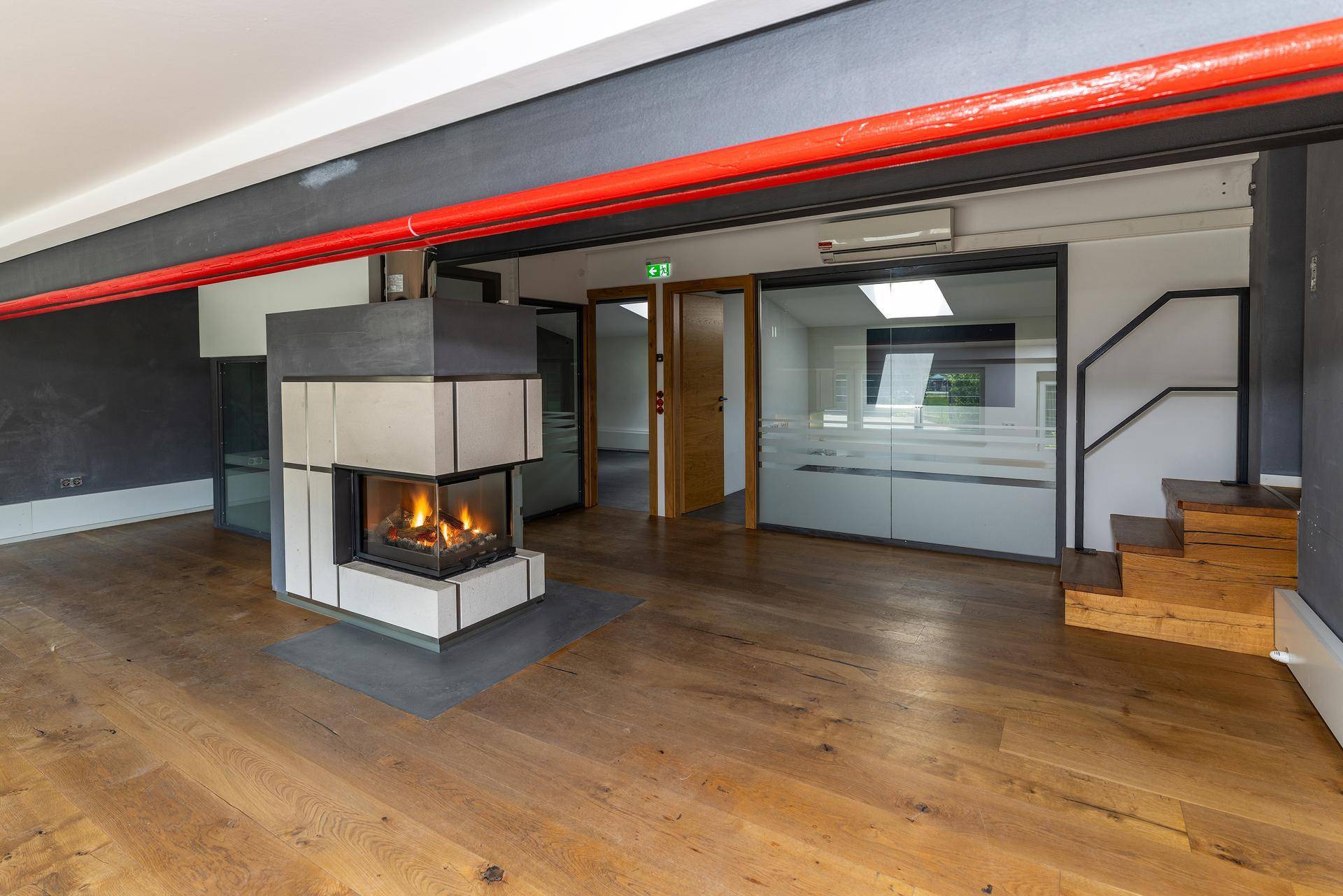 Geräumiger Innenraum mit modernem Kamin, Holzboden und industriellen Akzenten, ideal für Wohn- oder Geschäftszwecke.
