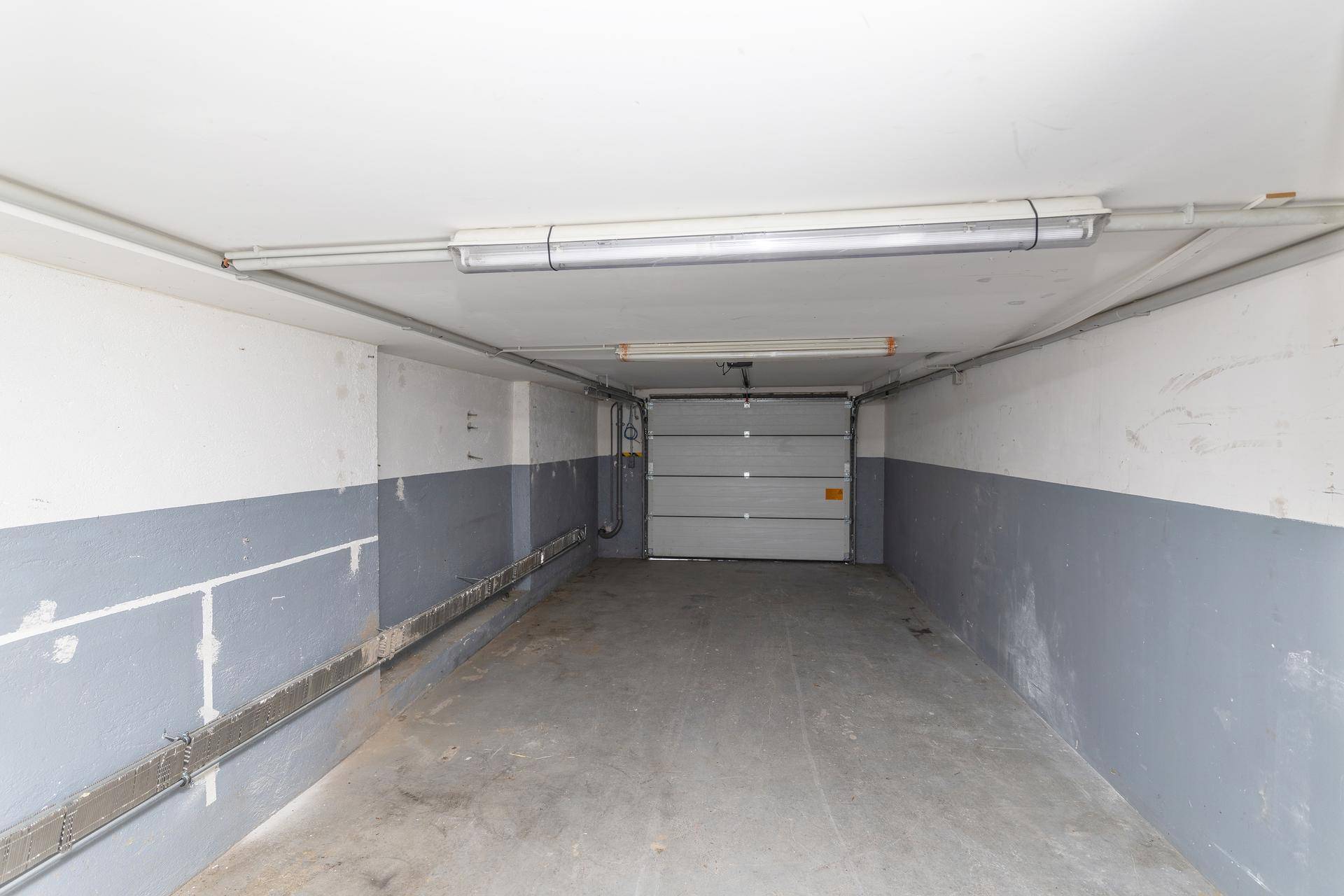Geräumige Garage oder Ladezone mit Betonboden und einer großen Rolltor-Einfahrt.