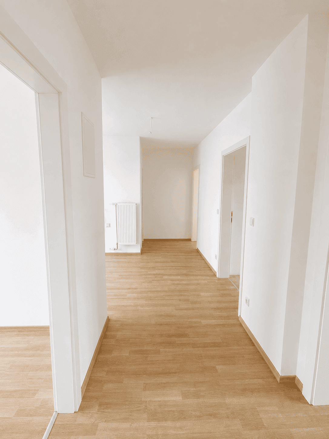 Langer, heller Flur mit Laminatboden, der zu den verschiedenen Zimmern führt.