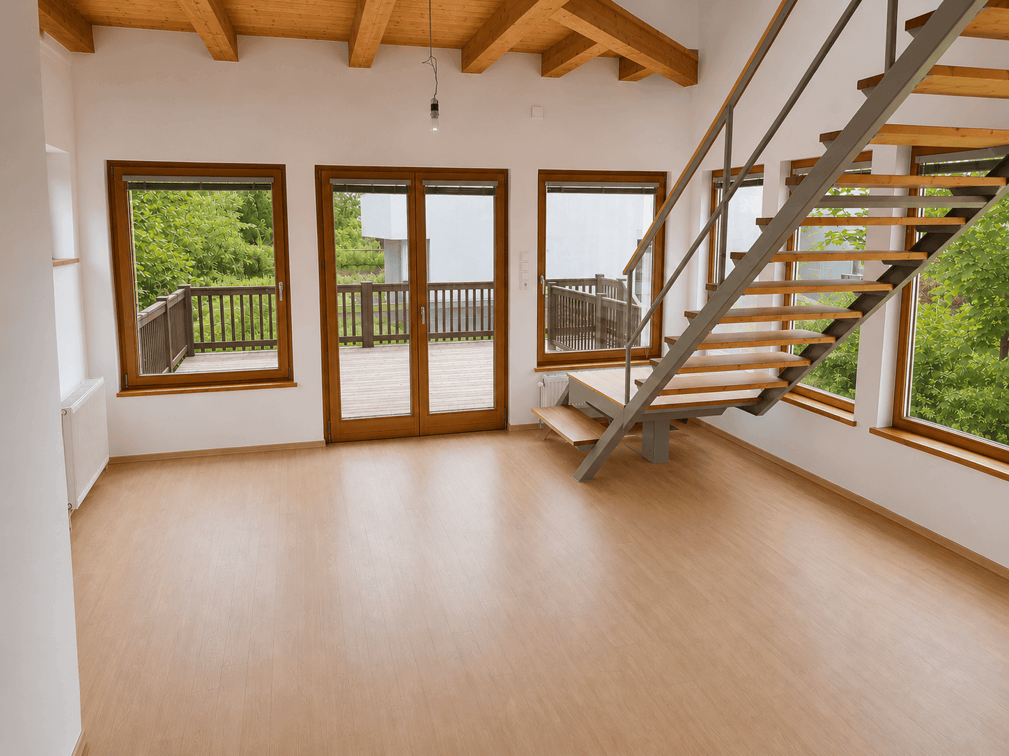 Geräumiges Wohnzimmer mit Holzbalkendecke, Laminatboden und direktem Zugang zur Terrasse.