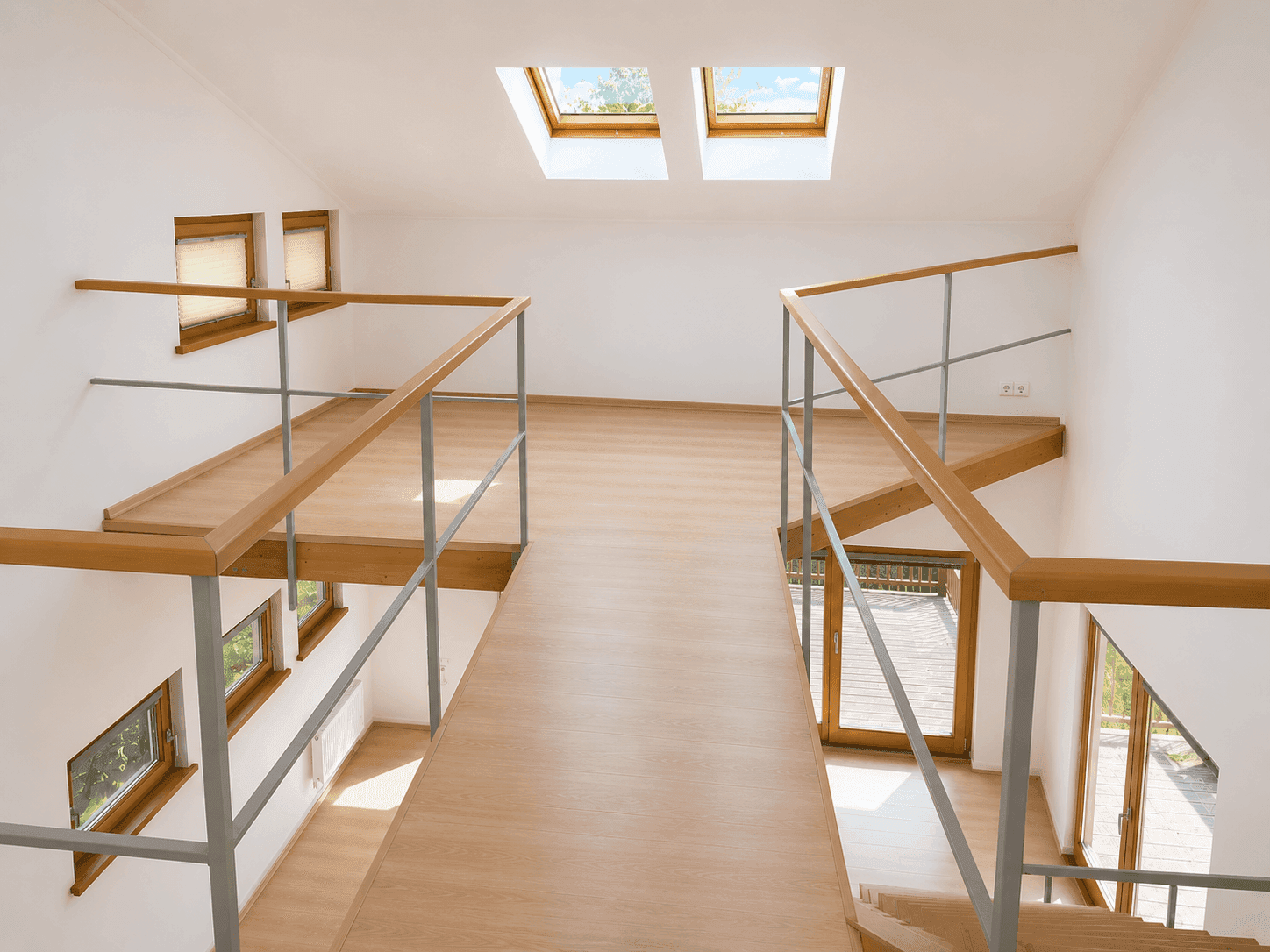 Heller Flur im Obergeschoss mit Dachfenstern, Holzgeländer und Blick in den Wohnbereich.
