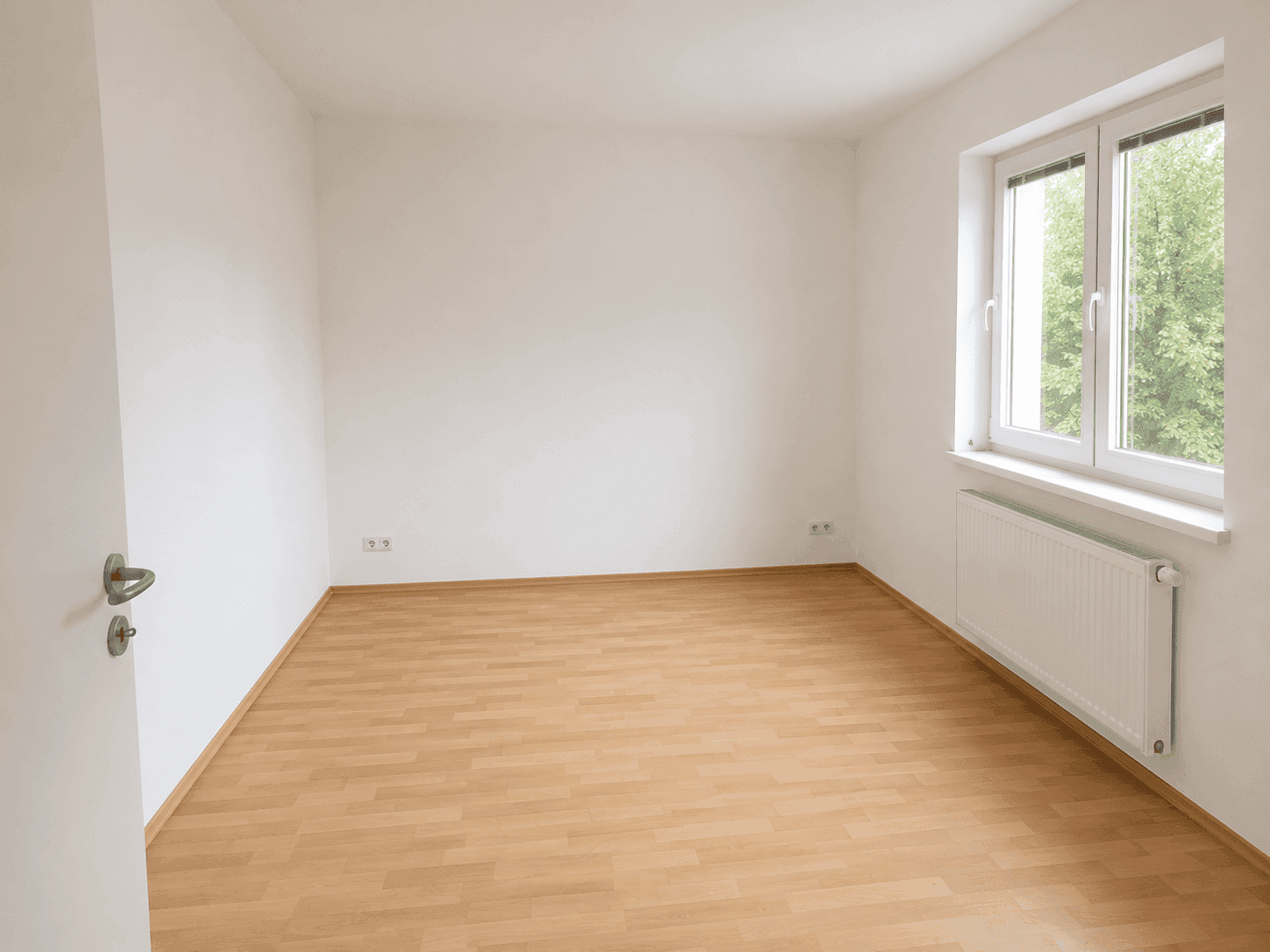 Helles Zimmer mit Laminatboden und einem Fenster, geeignet als Kinder- oder Gästezimmer.