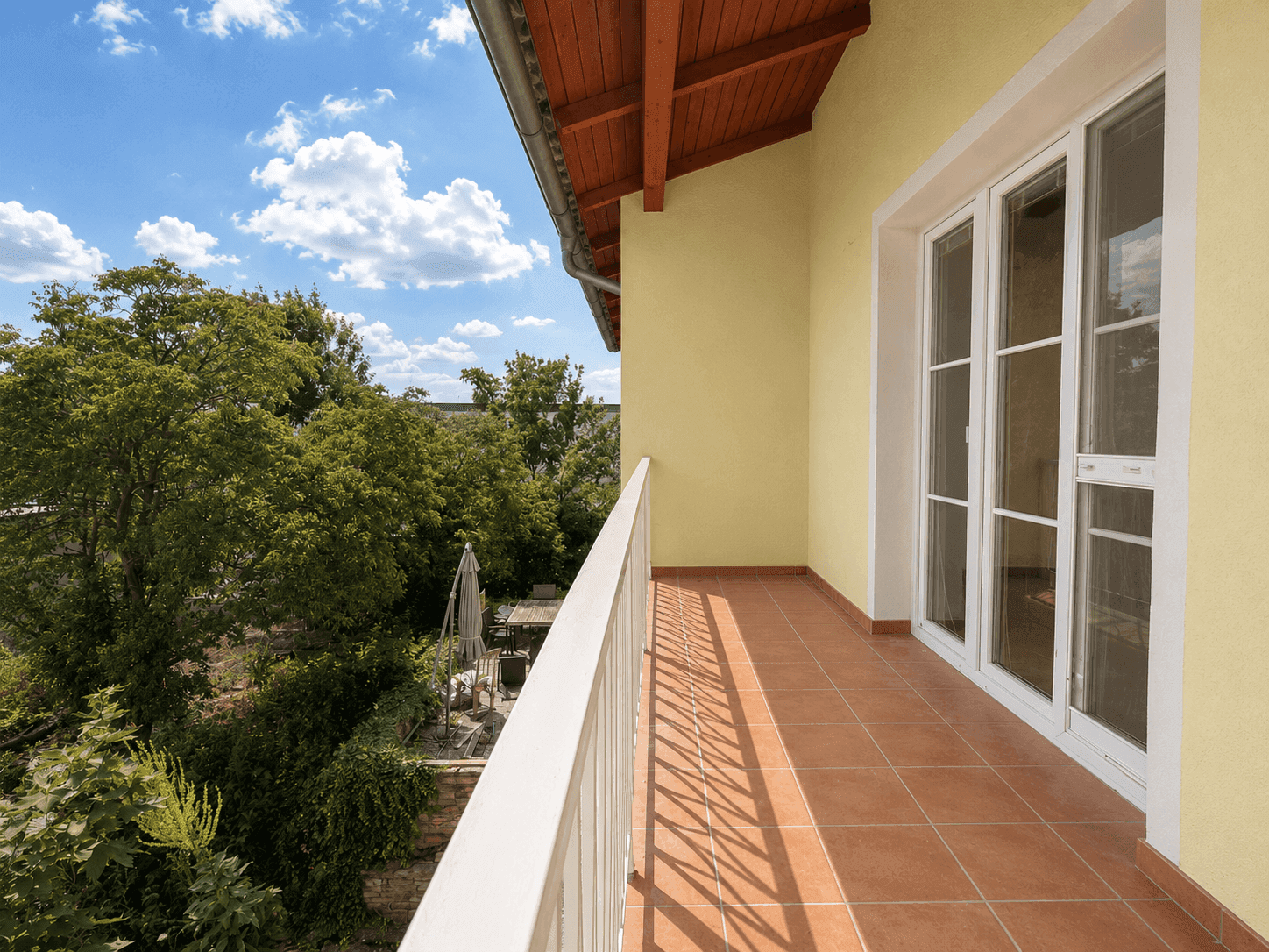 Langer Balkon mit Fliesenboden und Blick ins Grüne, ideal zum Entspannen.