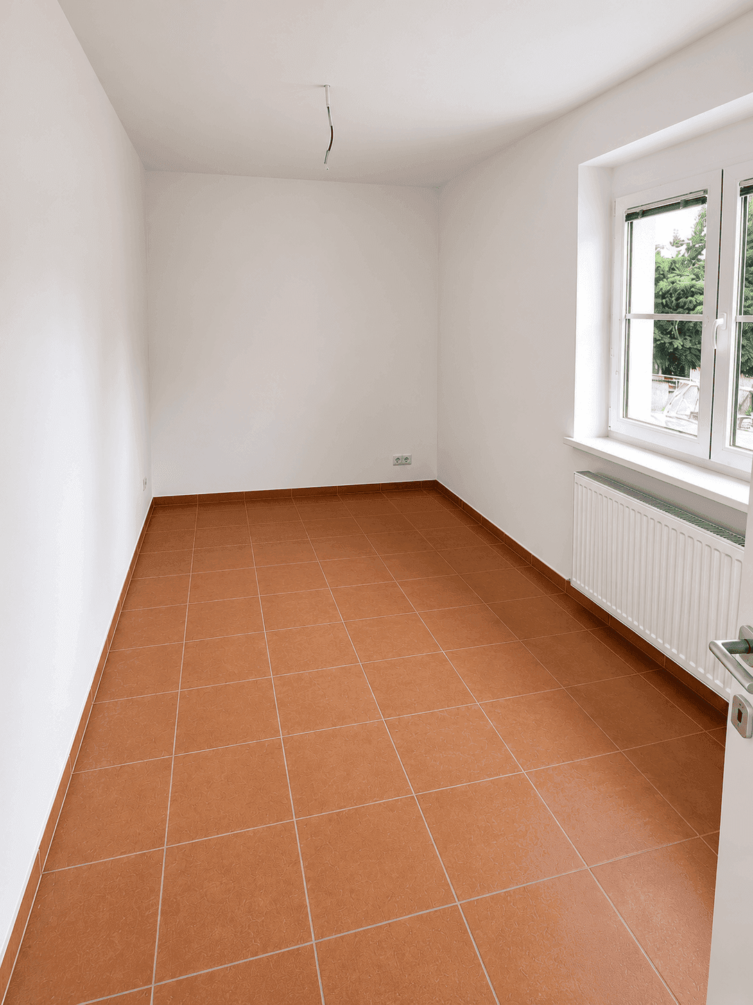 Ruhiges Zimmer mit Terracottaboden und Fenster, ideal als Schlaf- oder Arbeitszimmer.