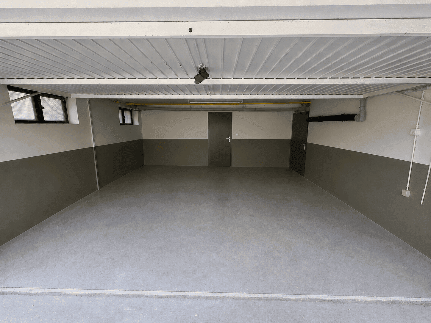 Geräumige Garage mit Betonboden und ausreichend Platz für Fahrzeuge und Lagerung.