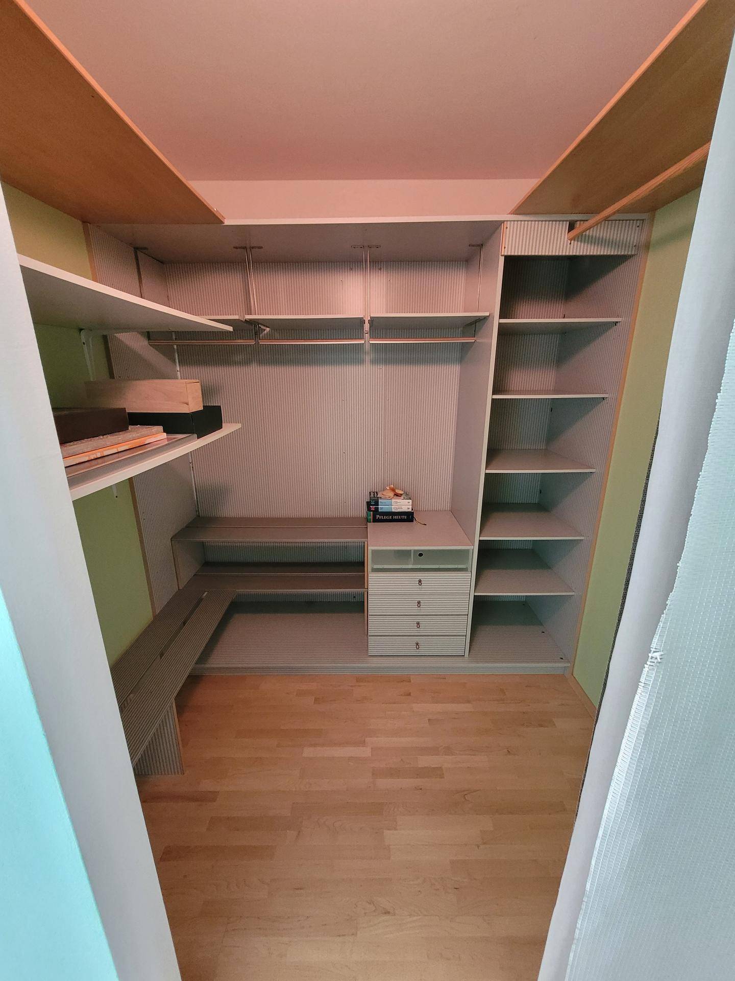 Begehbarer Kleiderschrank mit integrierten Regalen und Schubladen für Stauraum.