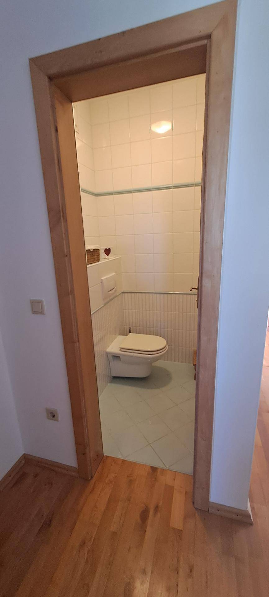 Kleines Gäste-WC mit Wand-WC und hellen Fliesen, funktional und sauber.