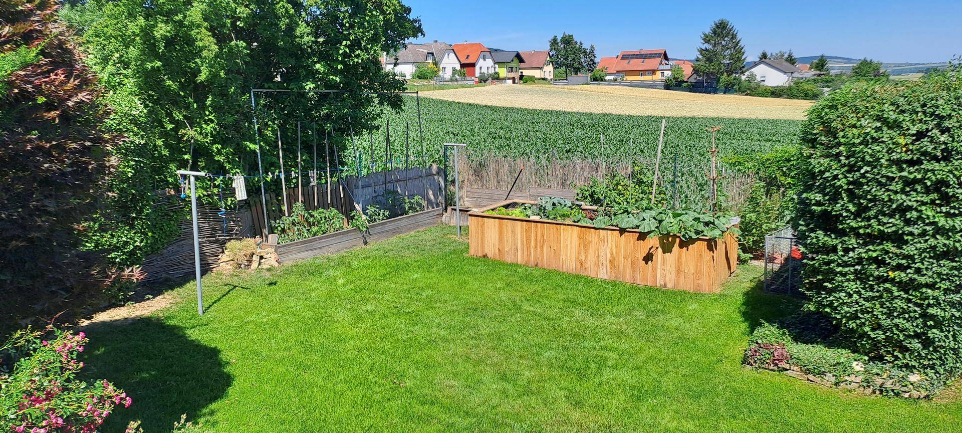 Gepflegter Gartenbereich mit Hochbeeten und weitem Blick über Felder und Landschaft.