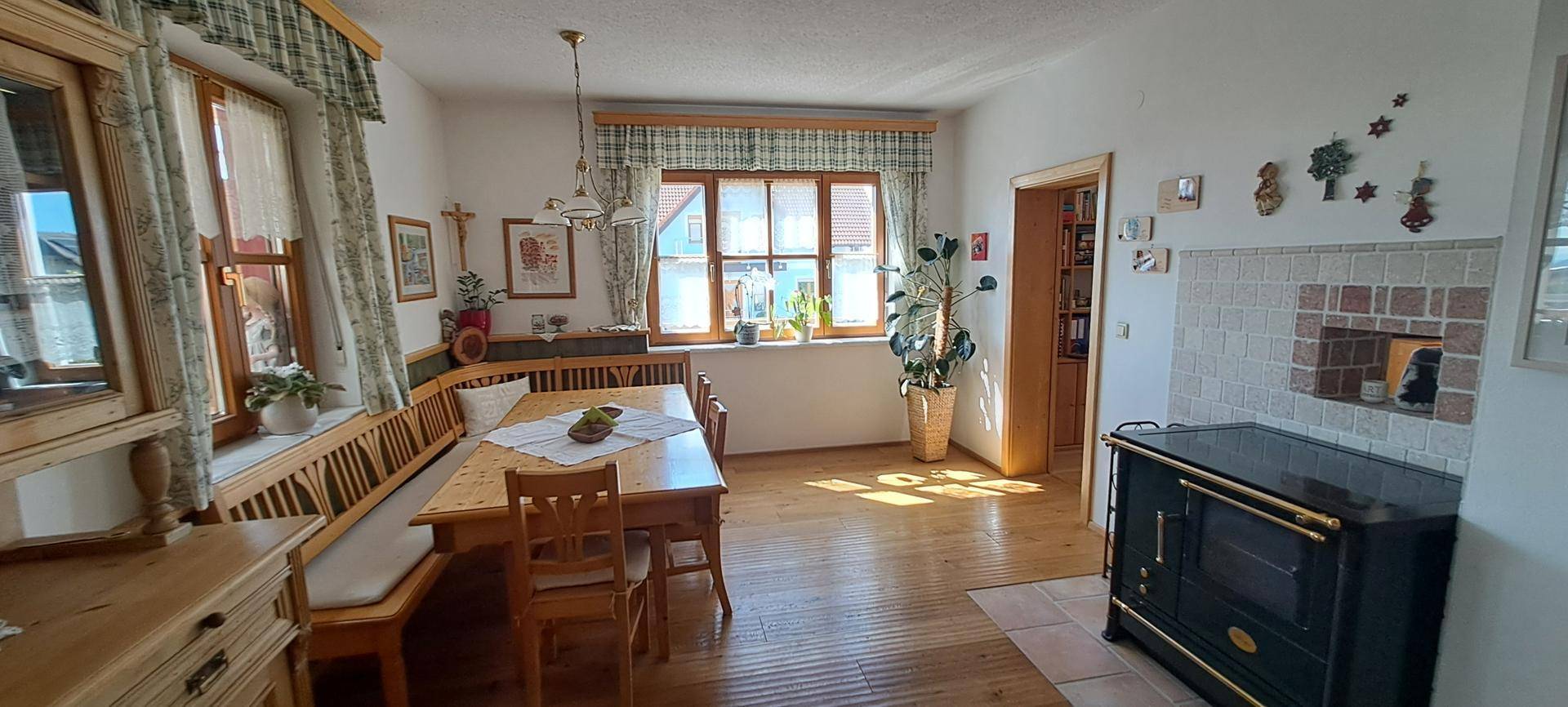 Gemütlicher Essbereich mit Holzboden, traditionellem Ofen und Blick in den Garten.