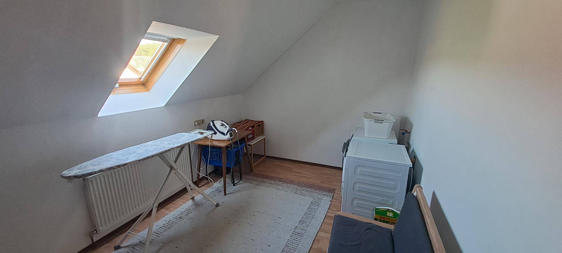 Praktischer Hauswirtschaftsraum im Dachgeschoss mit Waschmaschine und Dachfenster.