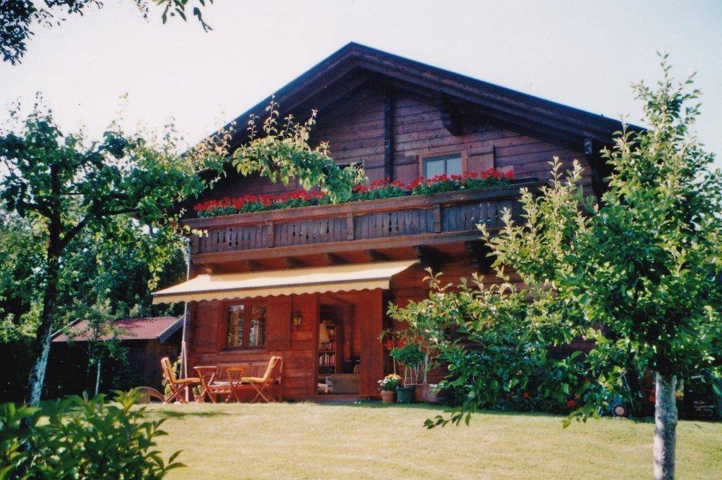 Idyllisches Holzhaus mit blühendem Balkon, sonniger Terrasse und großem Garten.