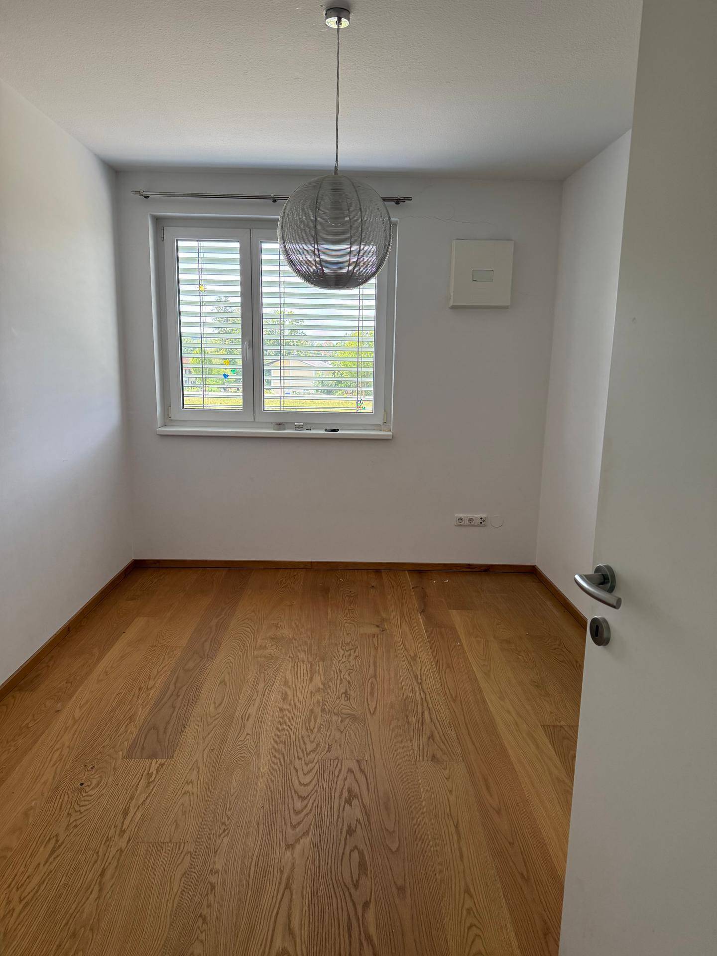 Heller Raum mit Holzboden und großem Fenster, ideal als Schlafzimmer oder Büro nutzbar.