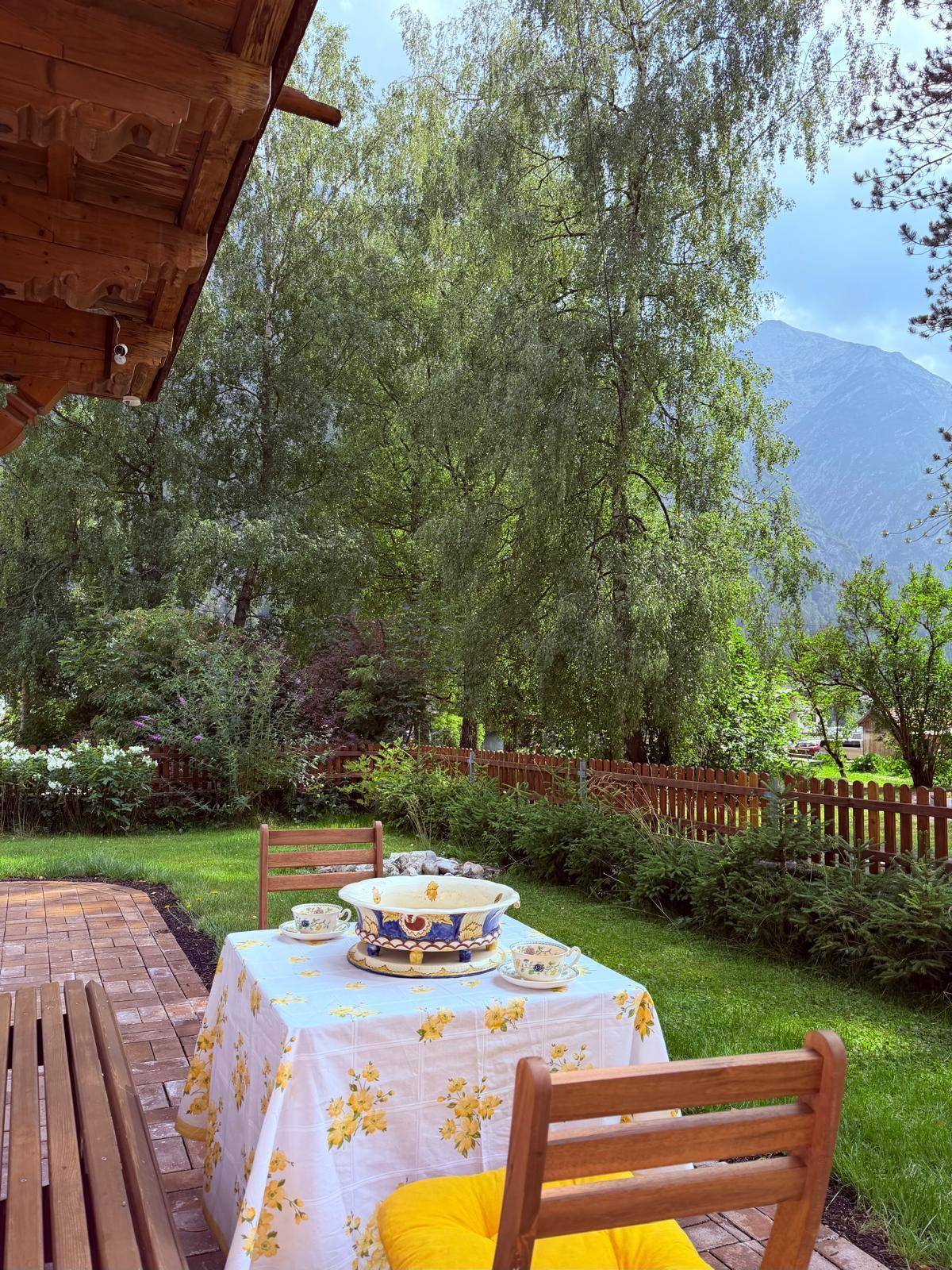 Gemütliche Terrasse mit Gartenmöbeln, umgeben von üppigem Grün und mit Blick auf die Berge.