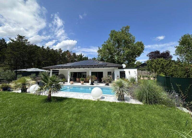 Panoramablick auf das Haus mit Pool, Garten und umgebender Natur an einem sonnigen Tag.
