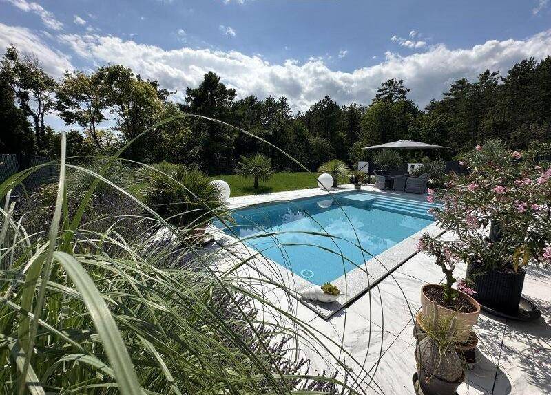 Entspannender Poolbereich umgeben von üppiger Vegetation und einer sonnigen Terrasse.