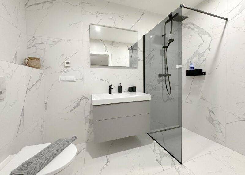 Modernes Badezimmer mit ebenerdiger Dusche, Waschtisch und Marmorfliesen.