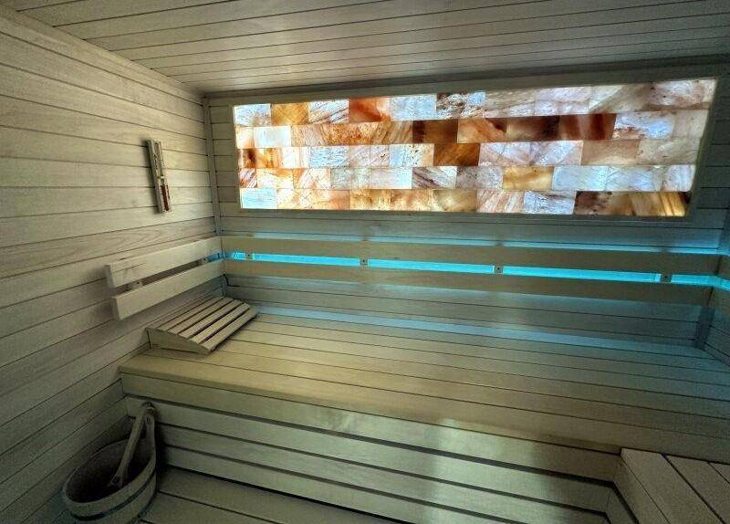 Innenansicht einer modernen Sauna mit Holzverkleidung und beleuchteter Salzwand für Entspannung.