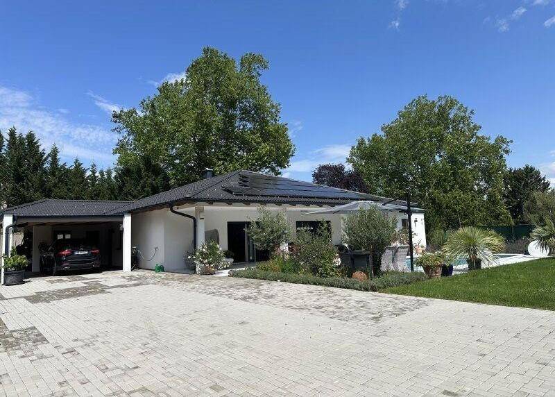 Vorderansicht des Hauses mit gepflasterter Auffahrt und überdachtem Carport.