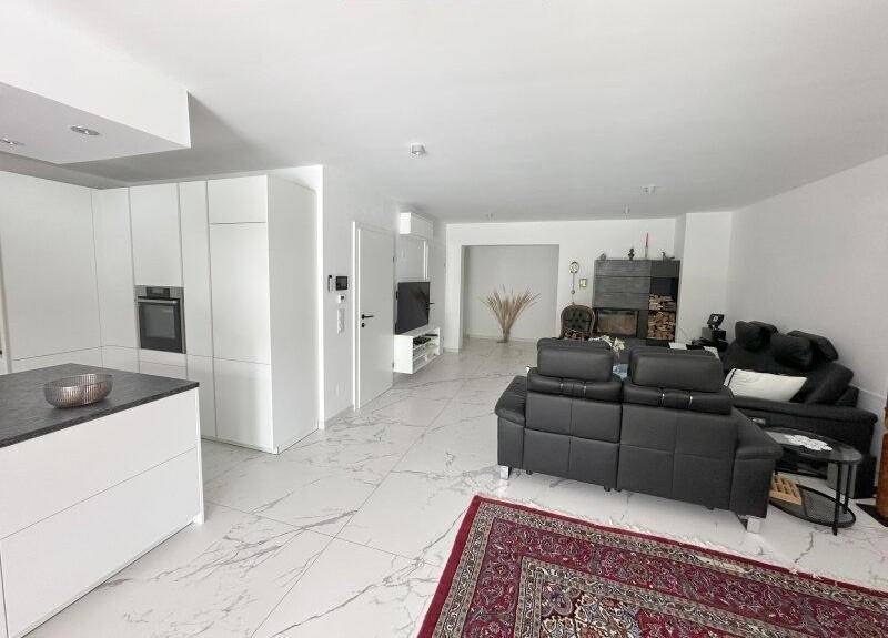 Gemütlicher Wohnbereich mit bequemen Sofas und Blick auf die moderne offene Küche.