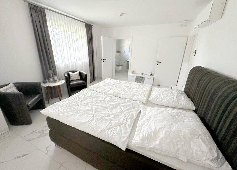 Komfortables Schlafzimmer mit Doppelbett und direktem Zugang zum modernen Badezimmer.