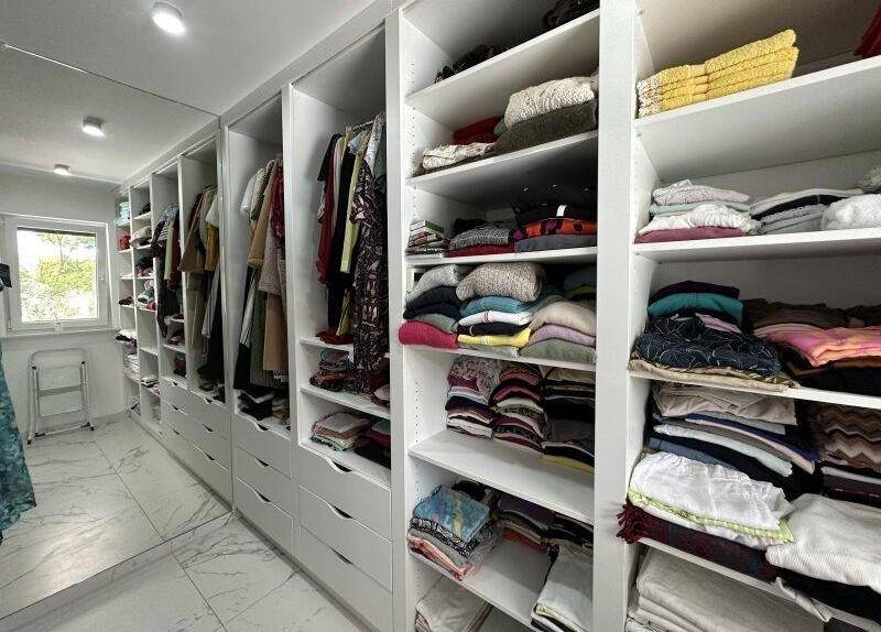 Geräumiger begehbarer Kleiderschrank mit vielen Regalen und Stauraum.