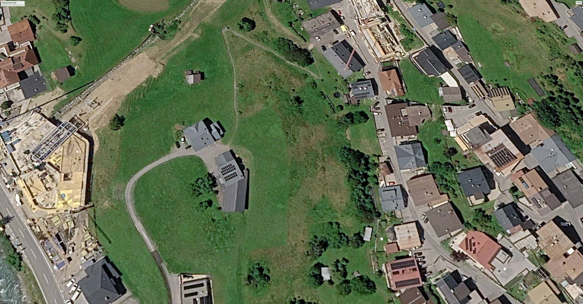 Panoramische Luftaufnahme einer Wohnsiedlung, umgeben von grünen Hügeln und einem Fluss in der Ferne.